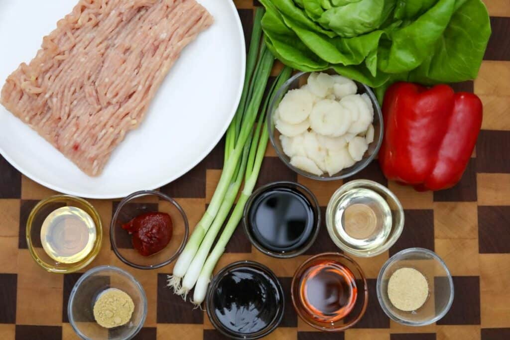 Ingredients for chicken lettuce wraps on a wooden cutting board