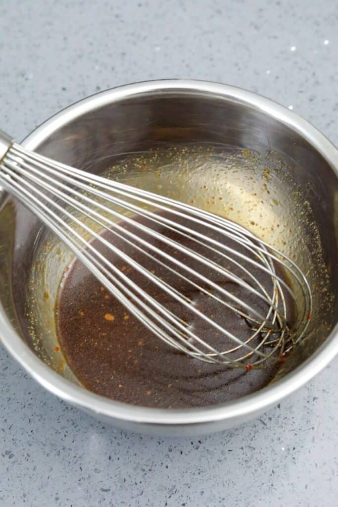 A bowl of sauce with a whisk