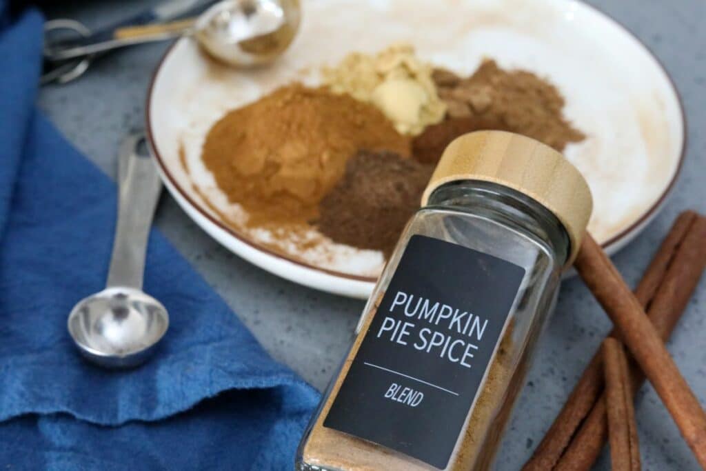 A plate of pumpkin spice blend ingredients and a labeled jar