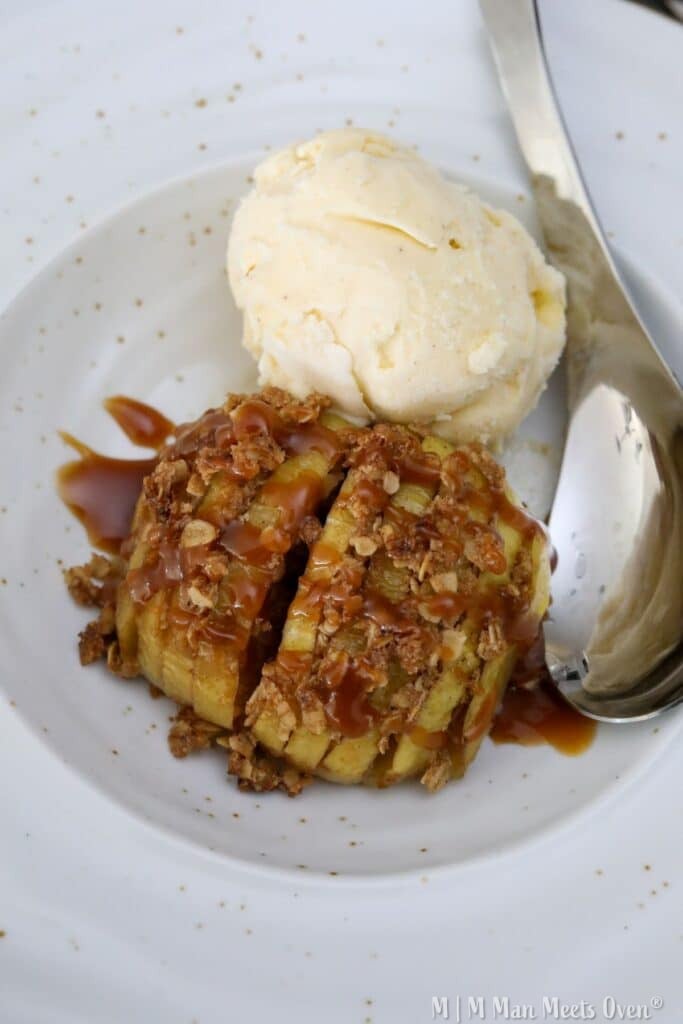 A white bowl with an apple and a scoop of ice cream and a spoon