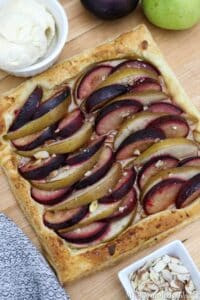 A pear and plum tart on a wooden cutting board