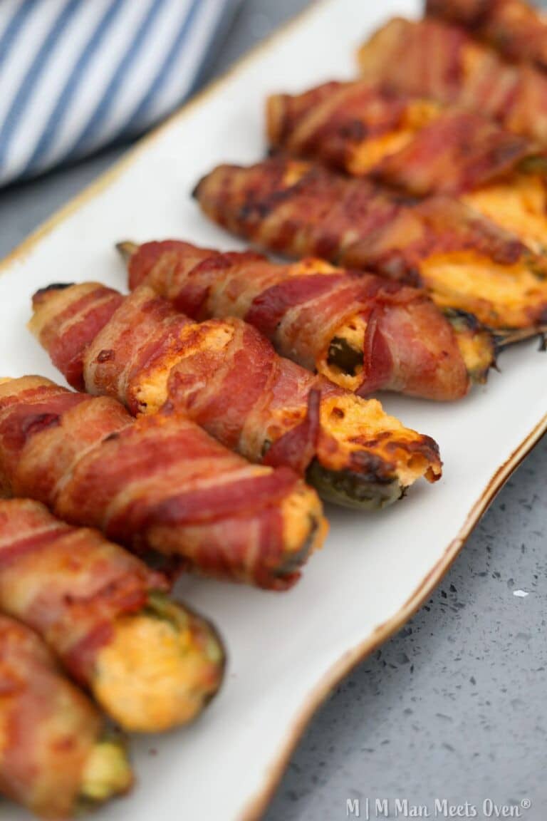 Bacon wrapped jalapeno poppers on a white platter