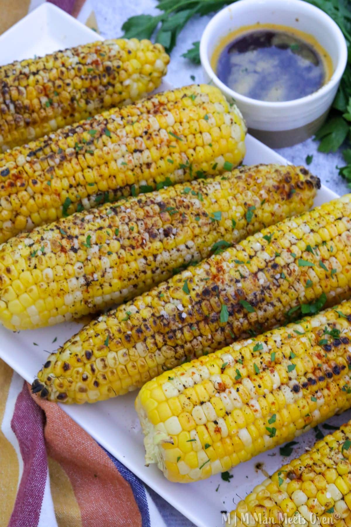 A white platter with grilled corn with cajun brown butter