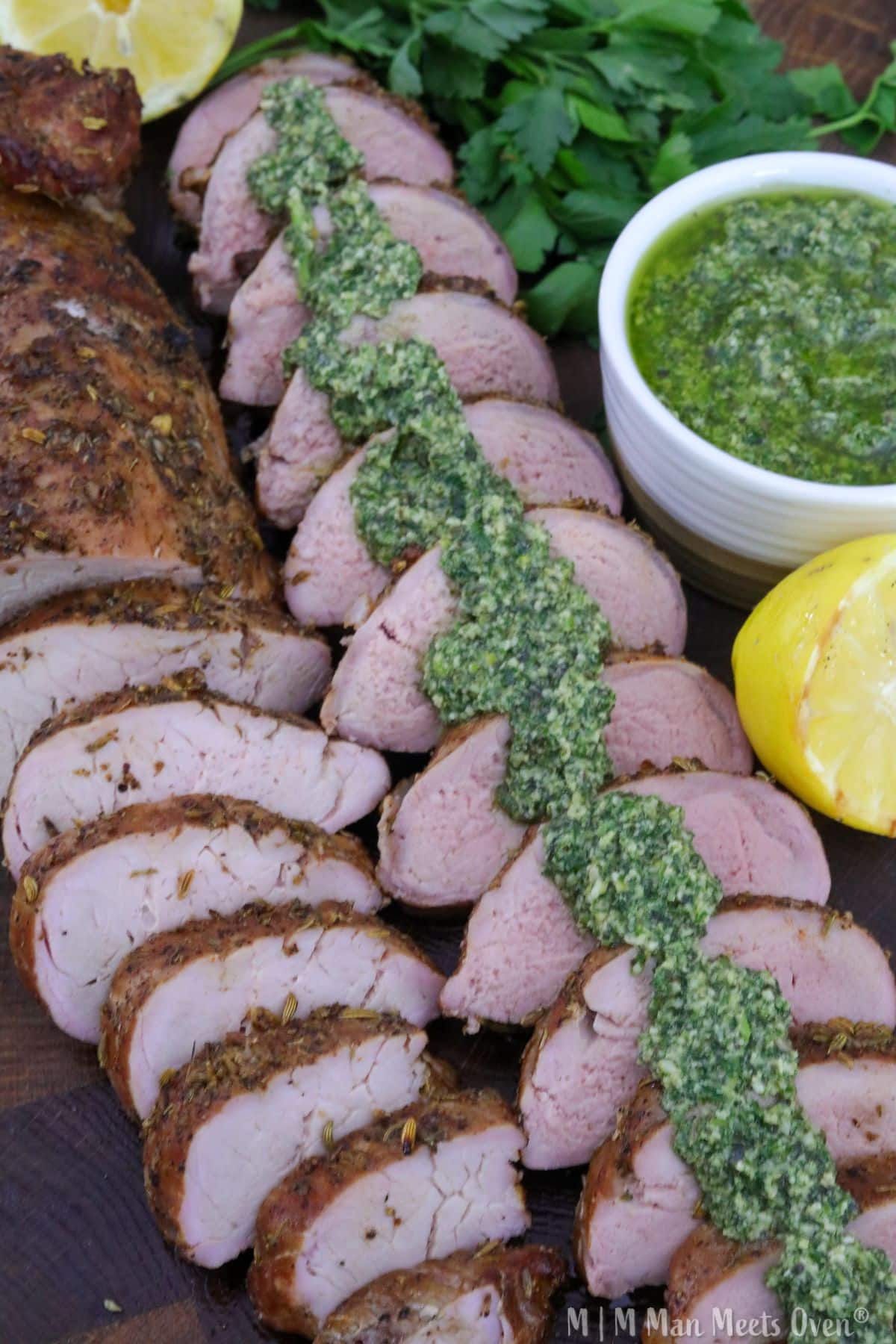 Sliced grilled pork loin herb pesto on a cutting board