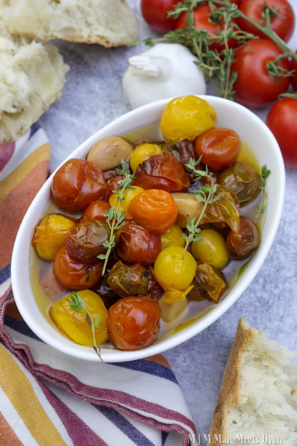 Cherry tomato confit in a white bowl with crusty bread