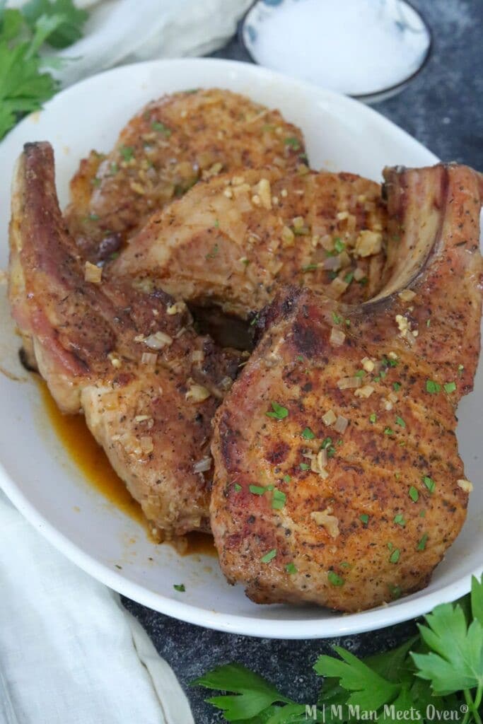 Four pork chops in a white bowl